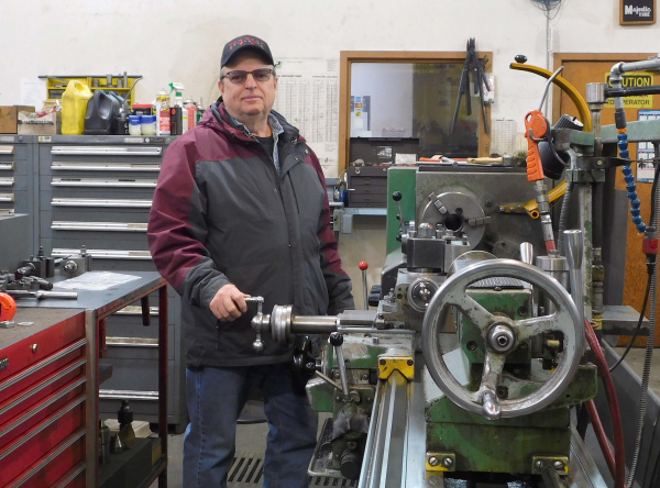 Carman Tufts stands beside a lathe he purchased in 1992 and is still used at the machine shop at Souris. 
