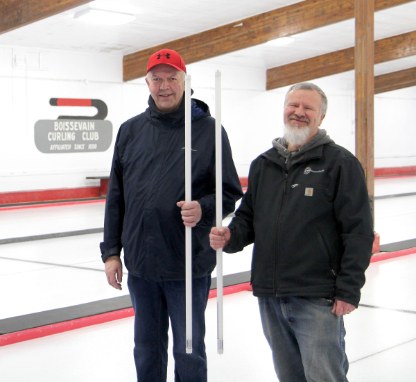 Boissevain Curling Club President Larry Rainne (left) and Copperman Electrical electrician Marc Loewen in the curling rink, which is scheduled for serious upgrades. Lighting in the building is to be changed to LED, free of charge thanks to Efficiency Manitoba. Work is to start soon. See story inside.   
